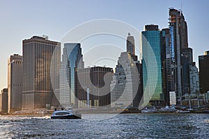 Ship going down river in New York City with skyline in background viewed from Brooklyn