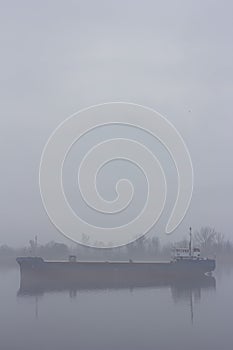 Ship on the IJssel river near Wilsum during a early sunny and misty morning.