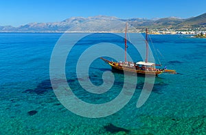 Ship like pirate schooners with two masts for sails near the rocks of the coast of Crete