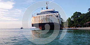 A ship at low tide aground. Palm trees on the beach