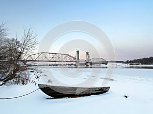 Ship mans boat on the beach at winter sunset with the train bridge on a background