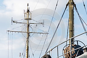 Ship mast of frigate, longboat or navy battleship. Metal mast pole. Ship awaits captain at docks. Lowered sails, blue sky on