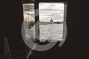 Ship moored to port seen through from inside the porthole of a ship