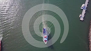 Ship moving across sea harbor port in ocean water, aerial birds eye view