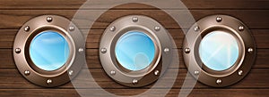 Ship portholes on wooden wall with sky view