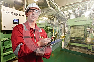 Ship`s mechanic near marine diesel generators on a merchant ship in the engine room