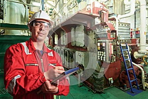 Ship`s mechanic near marine diesel generators on a merchant ship in the engine room