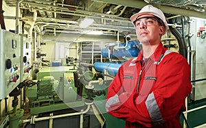 Ship`s mechanic near marine diesel generators on a merchant ship in the engine room