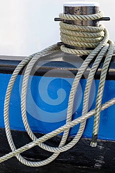 Ropes twisted around the iron bollard of a metal ship