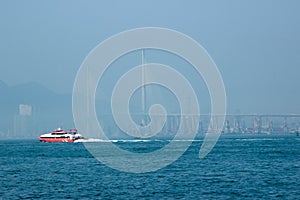 Ship sailing on blue sea bay on bridge background. Panoramic view ship floating on sea on car bridge background. Modern