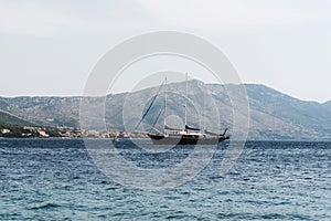 Ship sails along the shore with mountains. Korcula, Croatia