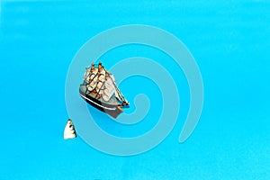 the ship sails and next to it a fish jumps out of the water, creative minimal concept on a blue background