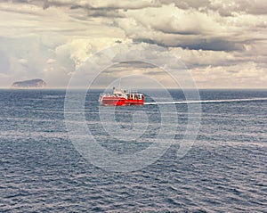 A ship sails past an island shrouded in a haze of mist. Silhouettes of ships on the horizon. Photo.