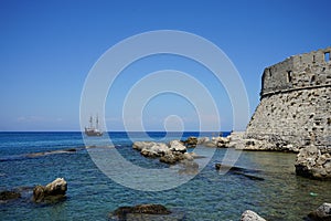 A ship with sails at sea at the walls of the Fort of Saint Nikolaos. Rhodes, Greece