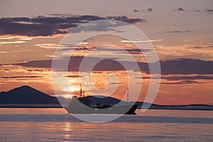 The ship in the sea against the backdrop of the rising sun.