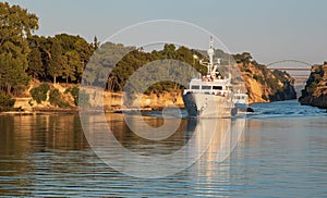 A ship with tourists sails along the Corinth canal between the picturesque coasts