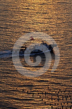 A ship traveling in the setting sun shining on the sea