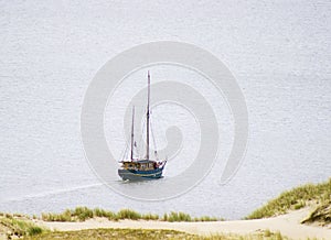 Ship under sail with the shore in the sea background