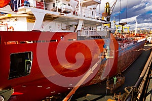 Ship undergoing maintenance in floating dock. Workers paint, repair vessel hull. Industrial, commercial shipyard