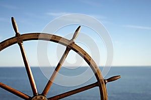 Ship wheel and blue sea on background