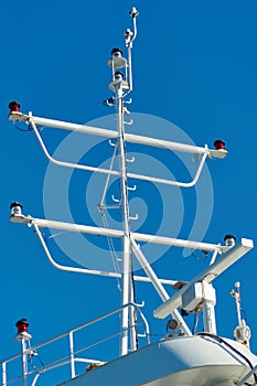 Ship mast with navigational equipment against blue sky photo