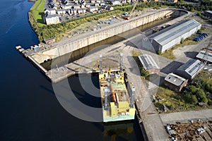 Shipbuilding construction ship in dry dock aerial view at shipyard harbour with scaffold