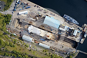 Shipbuilding construction ship in dry dock aerial view at shipyard harbour with scaffold