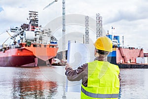 Shipbuilding engineer checking documents at the dock side in a port.