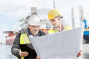 Shipbuilding engineer explains technical matters with a student worker.