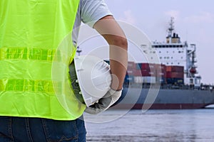 Shipbuilding engineer stands at the dockside in a port. Man is h