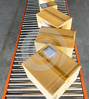 Shipment boxes sorting on rollers conveyor belt at distribution warehouse.