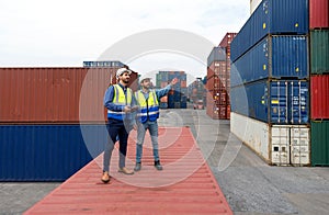 Shipment worker use a walkietalkie to point to container storage location, explain to colleague about planning for next shipment. photo