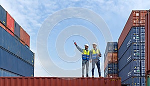 Shipment worker use a walkietalkie to point to container storage location, explain to colleague about planning for next shipment.