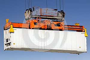 Shipping container lifted by gantry crane in the port