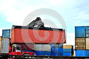 Shipping container loading by richtracker on the freight rail car at logistic warehouse port.