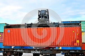 Shipping container loading by richtracker on the freight rail car at logistic warehouse port.