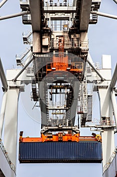 Shipping container unloaded by gantry crane from a industrial ship in the port