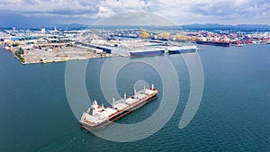 Shipping logistics business by the sea and terminal storage container ship with industrial city background aerial view from drone