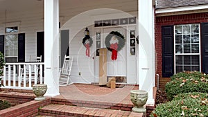 Shipping packages on front porch of house decorated for Christmas