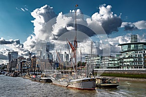 Ships And Boats Anchored On The River Thames In Front Of Modern Office Buildings In The City Of London, UK