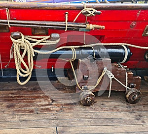 The ships cannon is secured with ropes on the deck of an old wooden sailboat