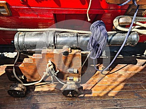 The ships cannon is secured with ropes on the deck of an old wooden sailboat