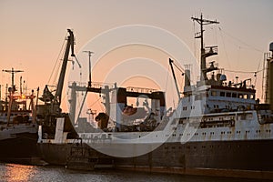 Ships in sea port on sunset background