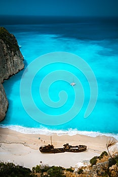 Shipwreck in Famous Navagio beach. Azure turquoise sea water and paradise sandy beach. Tourist visiting landmark on