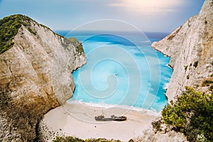 Shipwreck on Navagio beach. Azure turquoise sea water and paradise sandy beach in evening light. Famous tourist visiting