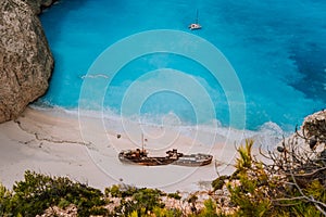 Shipwreck on Navagio beach. Azure turquoise sea water and paradise sandy beach in evening light. Famous tourist visiting
