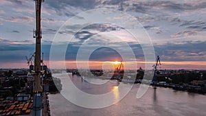 Shipyard with historical cranes in the industrial part on a riverside during sunrise aerial timelapse