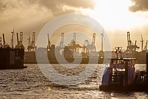 Shipyard (maybe Chinese?) in German port of Hamburg in fantastic yeloow sunny sunset and shinygold water photo