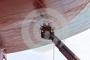 Shipyard workers cleaning ships hull. Ship in a dry dock.