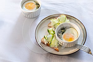 Shirred eggs Oeuf cocotte or baked eggs. healthy breakfast with eggs and spinach and toast with cucumber